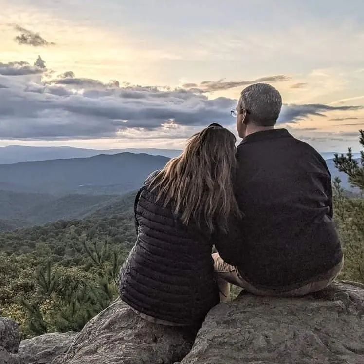 Stacey and Brad Shannon sitting together on a mountain overlook.